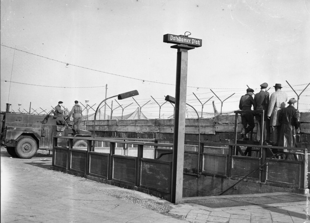 Soldiers outside the entrance to Berlin's Potsdamer Platz underground station next to a section of the Berlin Wall, circa 1961.