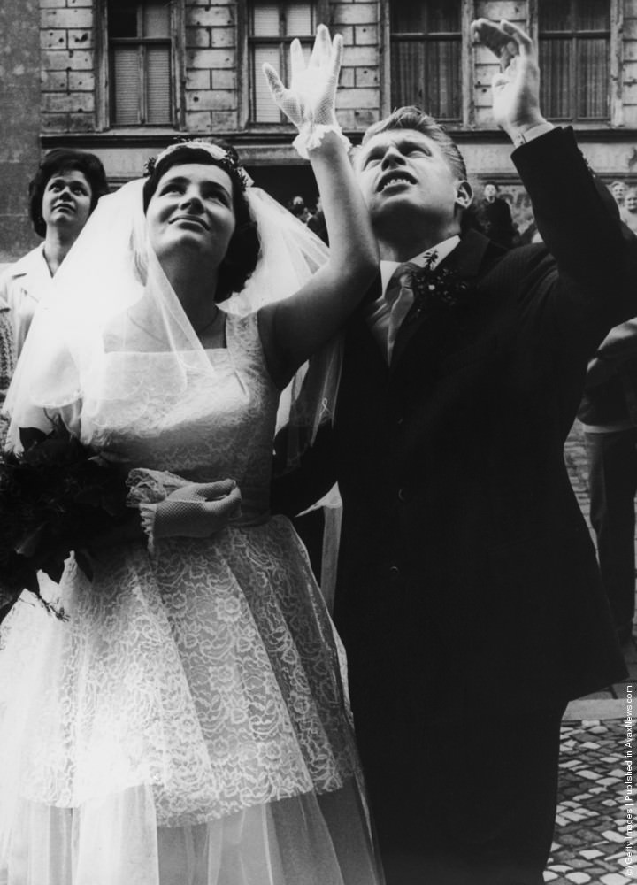 Dieter and Monika Marotz of Bernauerstrasse, Berlin, wave to relatives after their wedding, 8th September 1961.