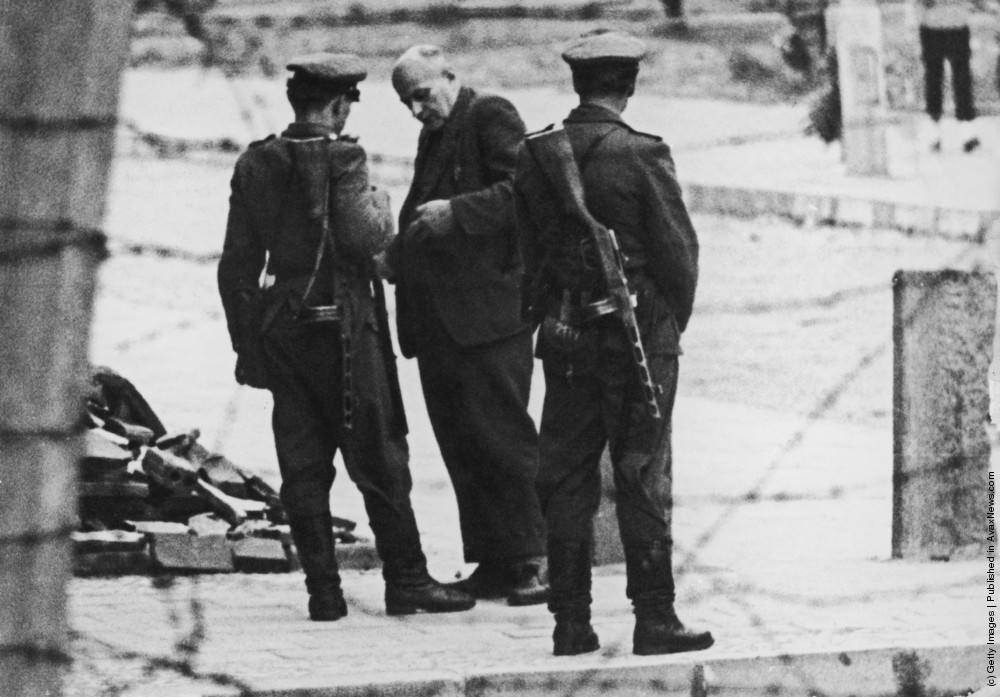 Members of the Volkspolizei, the East German national police, check an elderly man's papers at the Berlin Wall, 11th September 1961.