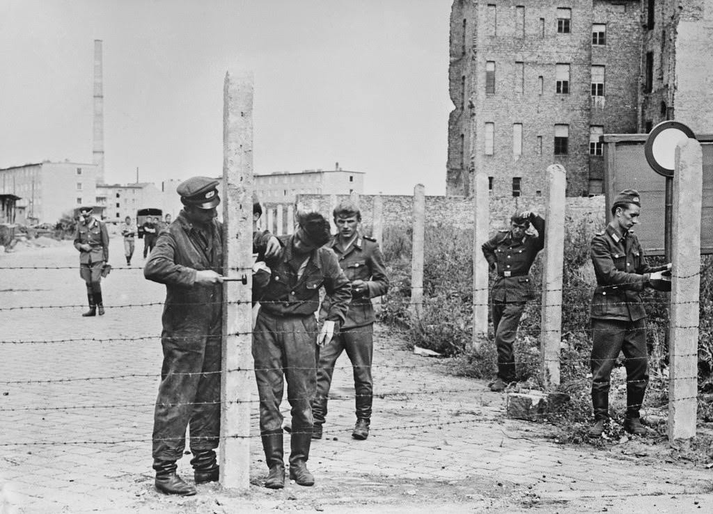 Soldiers of the East German National People's Army (NVA) erecting barbed wire fences to close off a street in preparation for the construction of the Berlin Wall, Berlin, Germany, 14th August 1961.