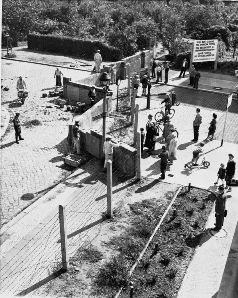 West Berliners at right watch East German construction workers erect a wall across Wildenbruchstrasse and Heidelbergerstrasse in West Berlin in August 1961.