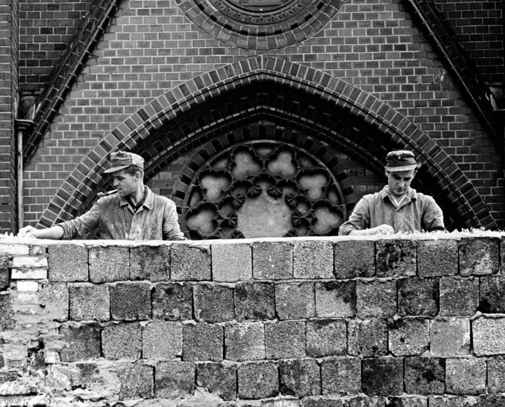 Blocking the church – Two East German workers working on a huge 15 feet hight Wall put pieces of broken glass on the top to prevent East Berliners from escaping.