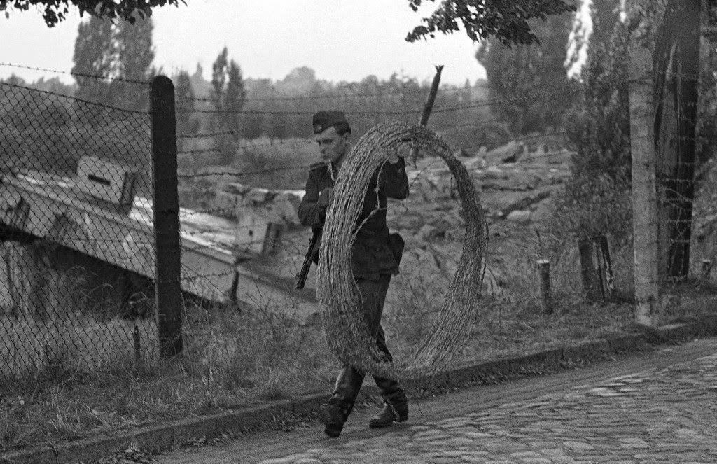 East German soldier carries a big roll of barbed wire along the border separating the British and Soviet sectors of Berlin August 21, 1961.