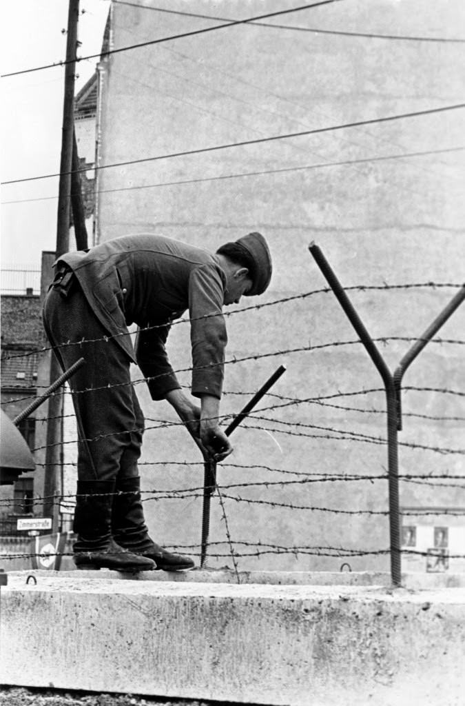 An East Berlin soldier secures a steel bar to hold the barbed wire atop the Berlin Wall on sector border in Berlin near Friedrichstrasse in Germany on Sept. 30, 1961.