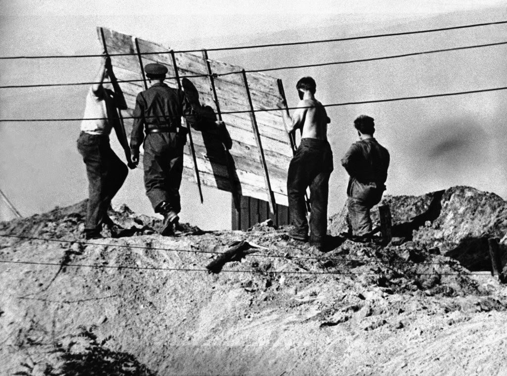 Nailed together planks are placed into position by East Berlin soldiers as they labor to reinforce trench (foreground) along the East-West border of Berlin at Neukoelln-Baumschulenweg in the southern part of the city on Oct.9, 1961.