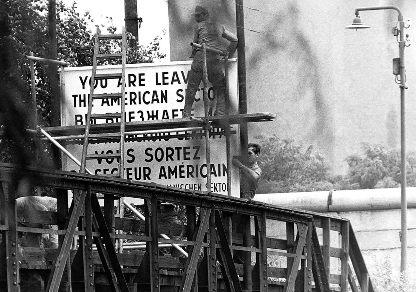 Workers set up a sign warning pedestrians they are leaving the American sector of Berlin, Germany, on Wiener Strasse (Vienna Street) in the district of Kreuzberg in West Berlin, on August 13, 1961.