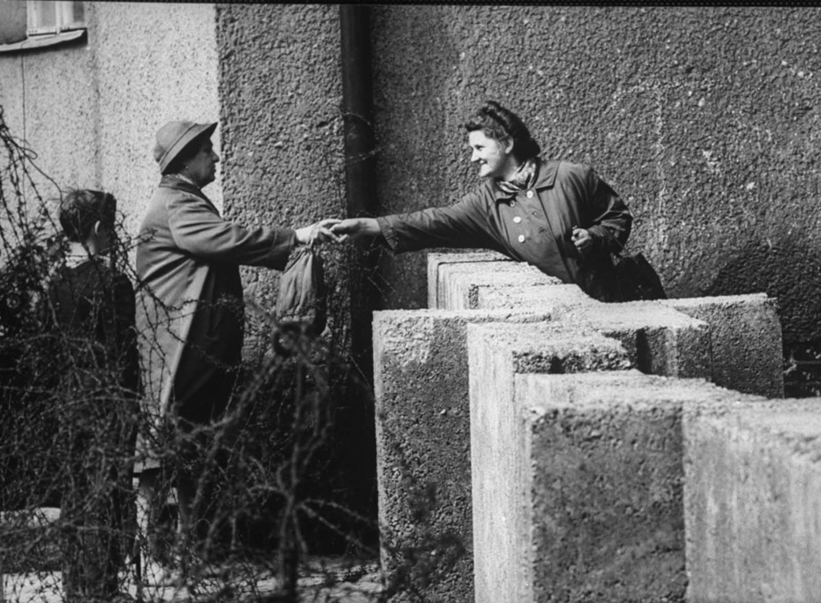 Friends reach across the barrier to touch each other in August 1961.