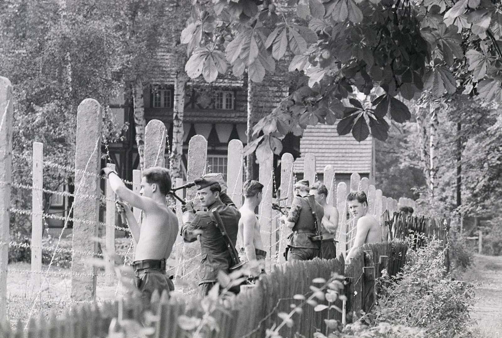 Communist People’s Police officers string barbed wire along a fence between East and West Berlin in September 1961.