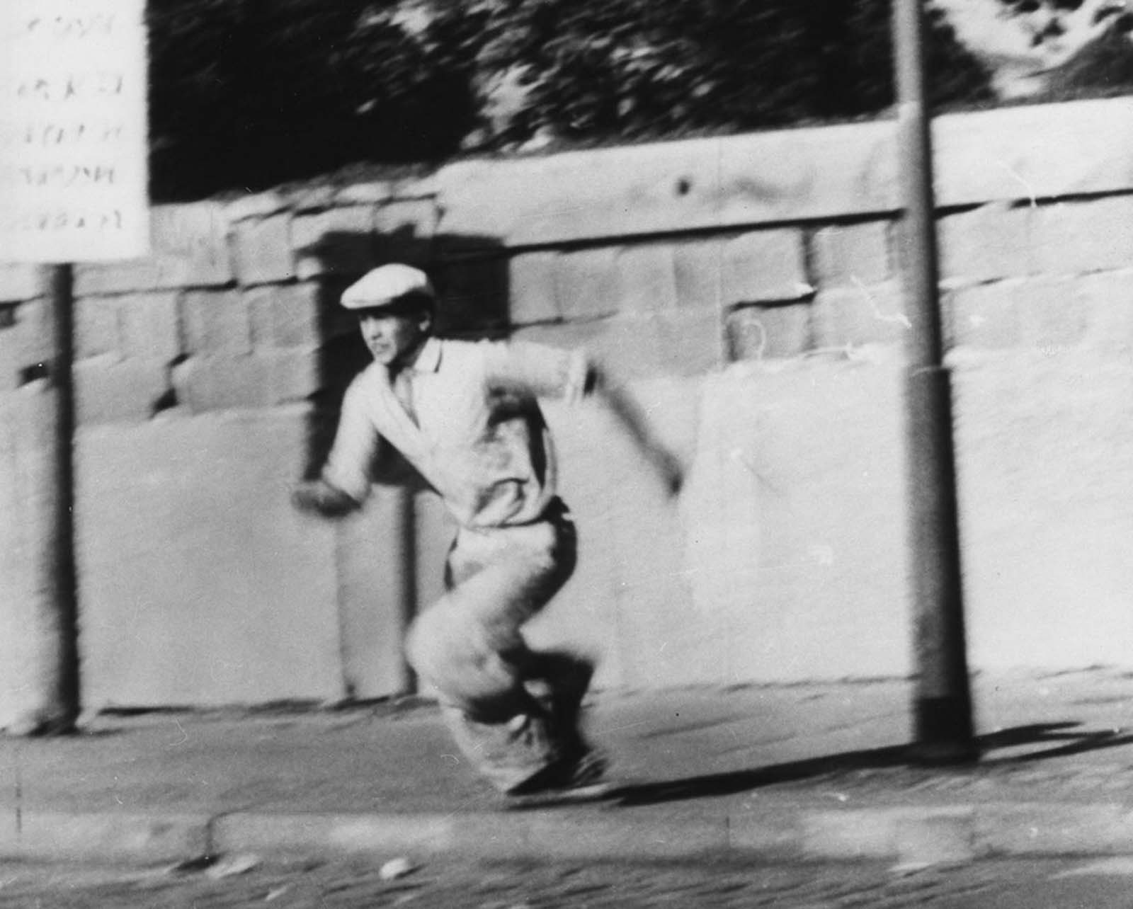 A refugee runs during an attempt to escape from the East German part of Berlin to West Berlin by climbing over the Berlin Wall on October 16, 1961.