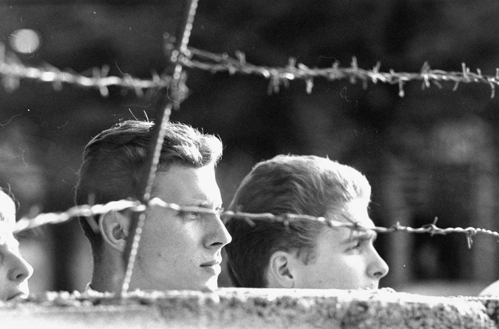 West Germans peer over part of the newly constructed Berlin Wall while waiting for relatives to return from the eastern sector in August 1961.
