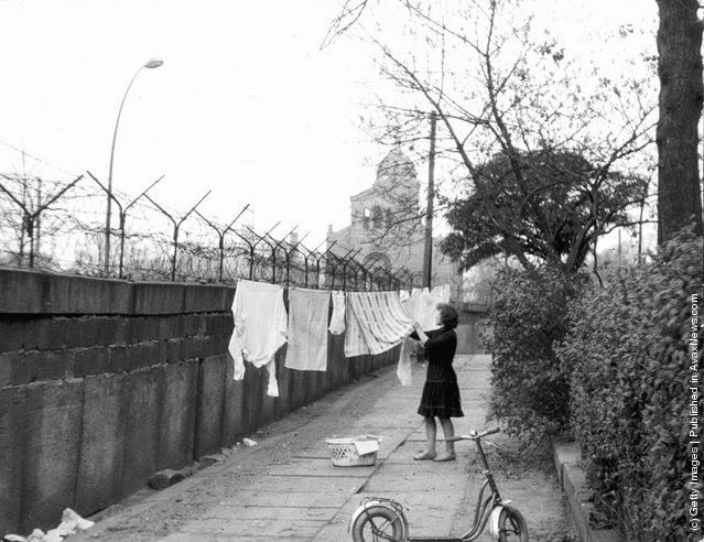 A German women hangs clothing out to dry on a line strung between a tree and the Berlin Wall, Germany, November 13, 1963