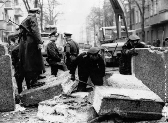 Officers inspecting the damage to the Berlin Wall, East Germany, and making preparations for its repair, after an East German rammed the Wall with an army car and successfully escaped, 1963.