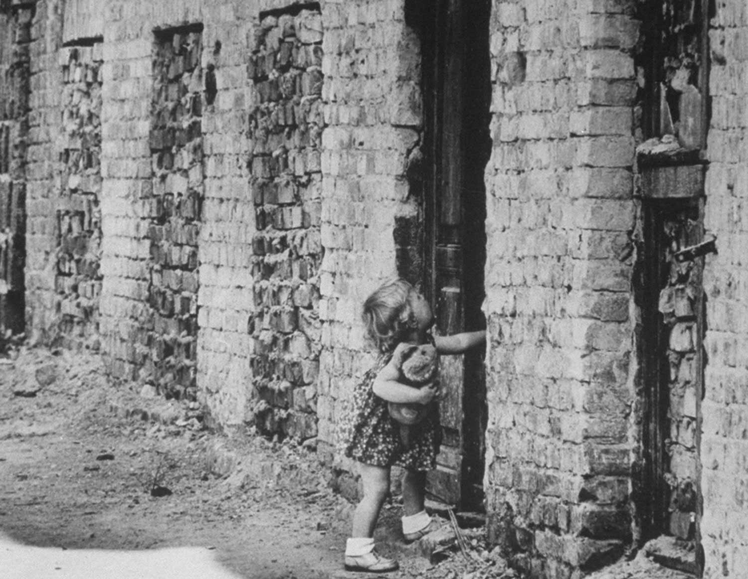 A West Berlin toddler attempts to open a sealed door of a house that has become part of the Berlin Wall in August 1961.