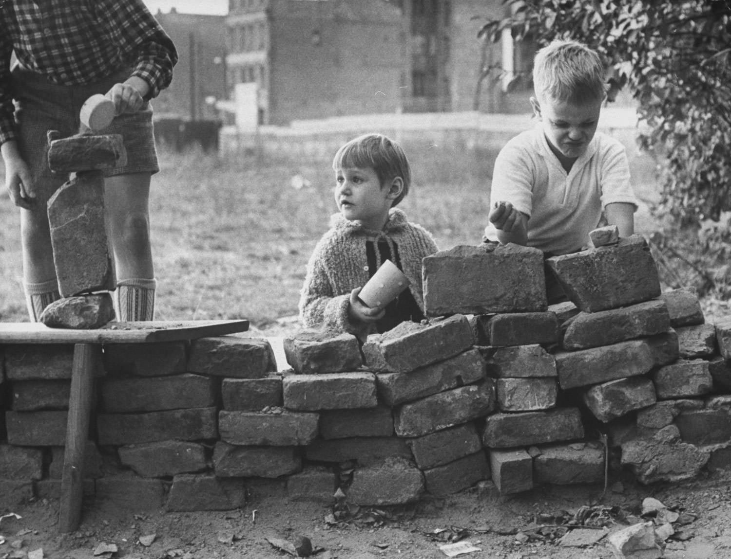 West Berlin children, from left, Peter Friedrich, 5, Katrin Kuhl, 4, and Jurgen Bottcher, 8, build a pretend Berlin Wall in a vacant lot in October 1961.