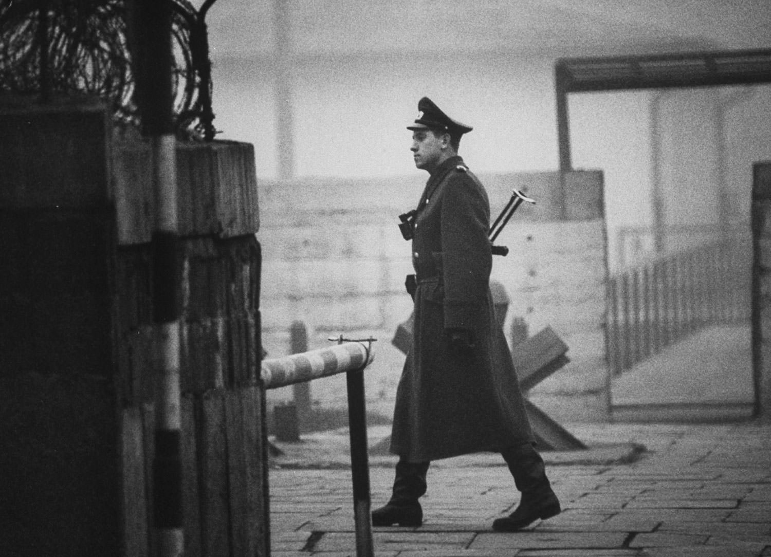 An East German policeman, known as a Volkspolizei or "people's police" — Vopo for short — walks at Checkpoint Charlie between East and West Berlin in October 1962.