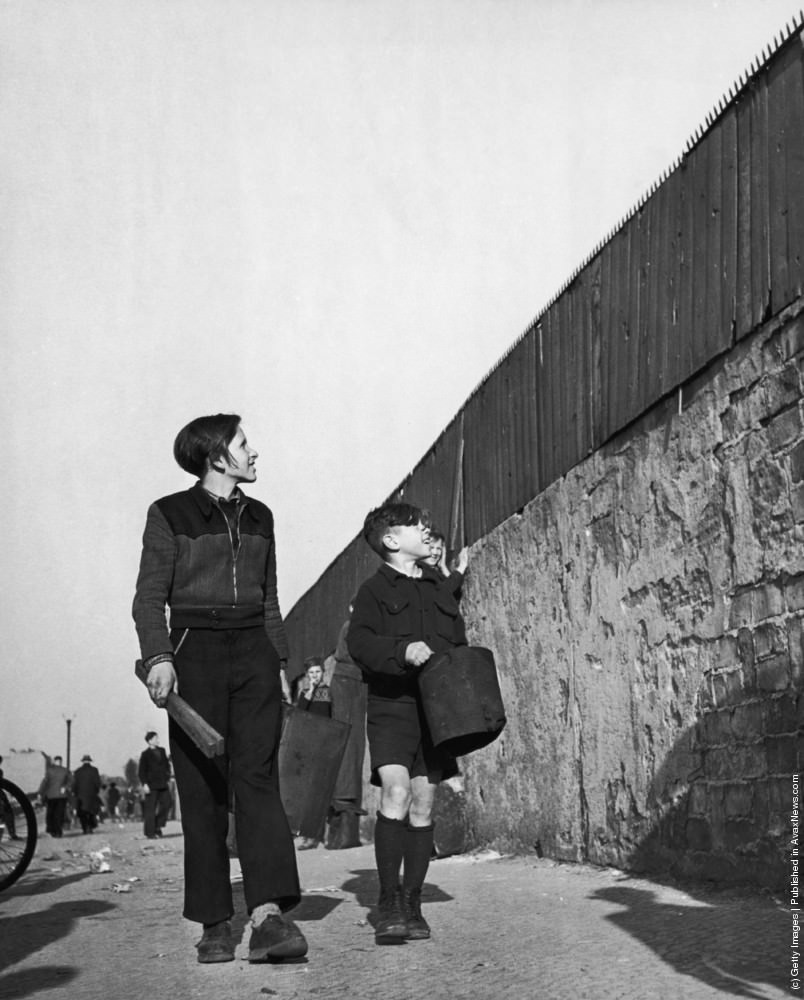 Boys bring buckets to stand on for a view over the wall of a sports stadium in Berlin, 8th January 1961.