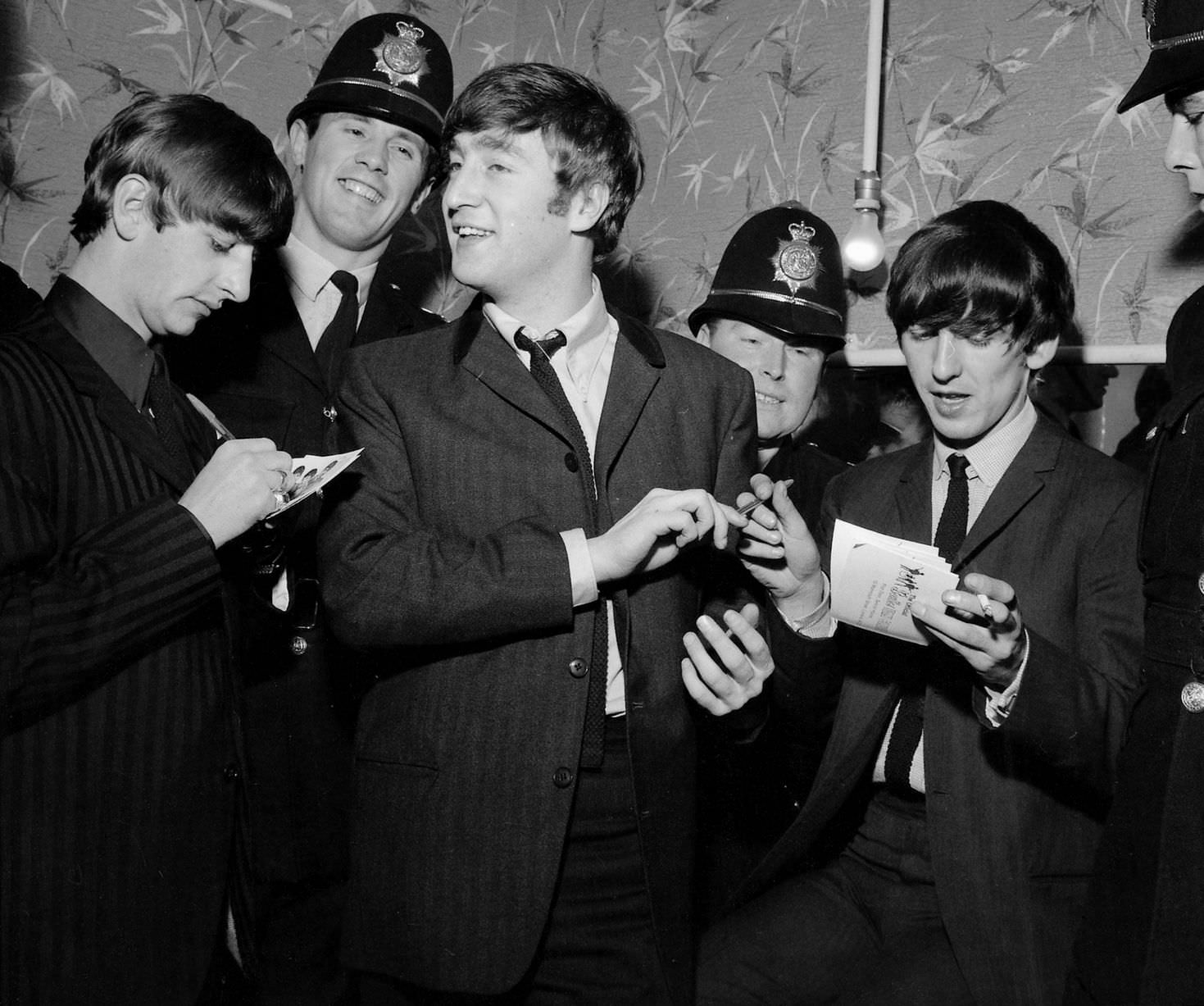 Beatles members, Ringo Starr, John Lennon and George Harrison sign autographs for police officers whilst in Birmingham, in November 1963.