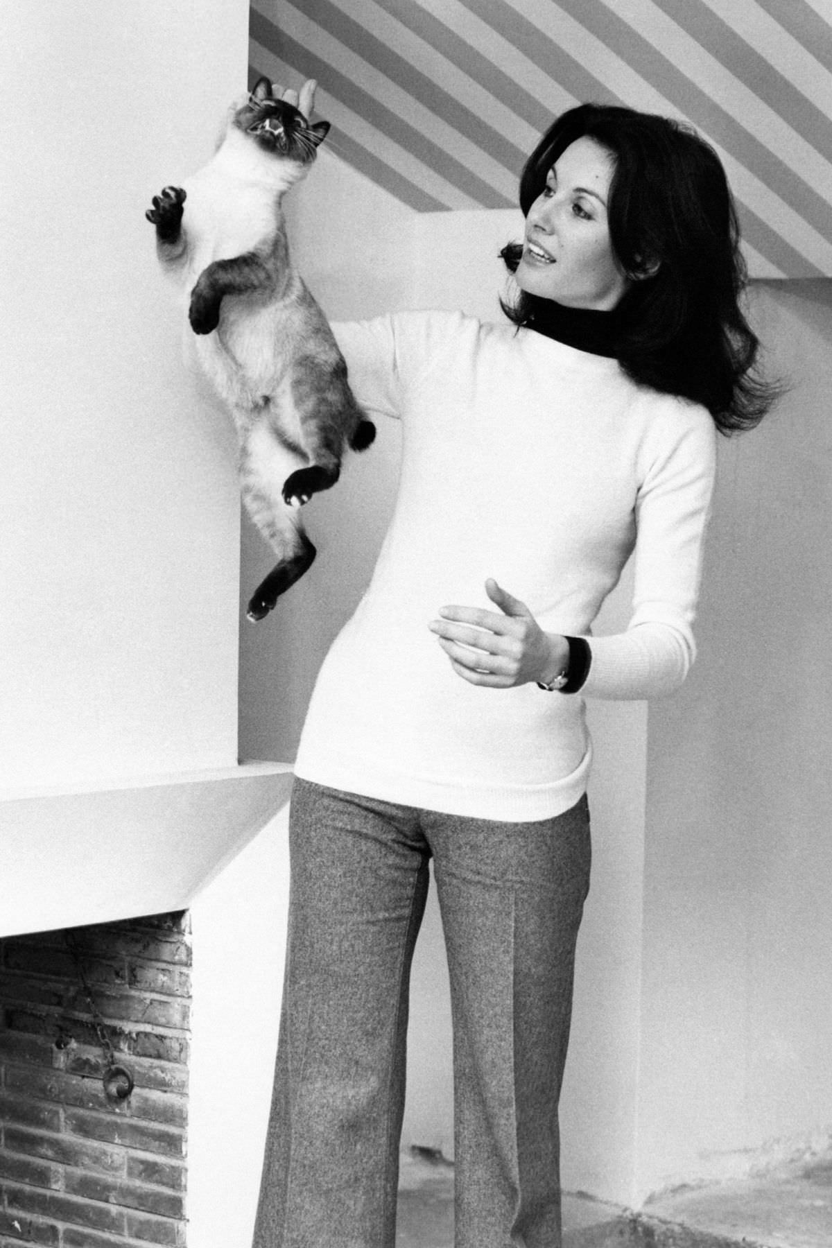 Italian television presenter and actress Gabriella Farinon picking her cat with one hand.