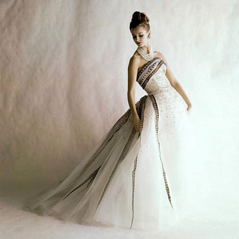 Anna Carin Bjorck in a strapless ball gown made of white tulle with gold pailletes and pheasant feather ribbons by Balmain, June 1960