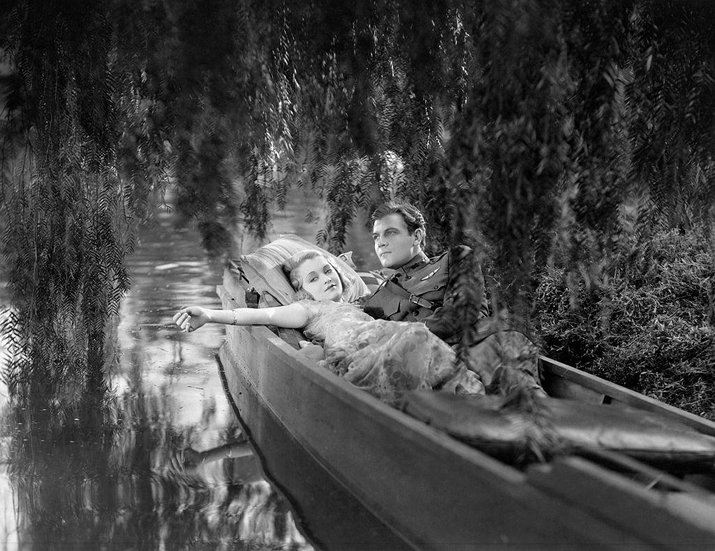 Constance Bennet, as Doris Kendall, and Joel McCrea, as Barry Craig, recline in a rowboat in the film Born to Love.
