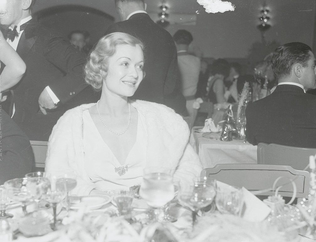Constance Bennett, smiles prettily from her table in the Agua Caliente Hotel where she celebrated New Year's Eve with scores of members of the film colony.