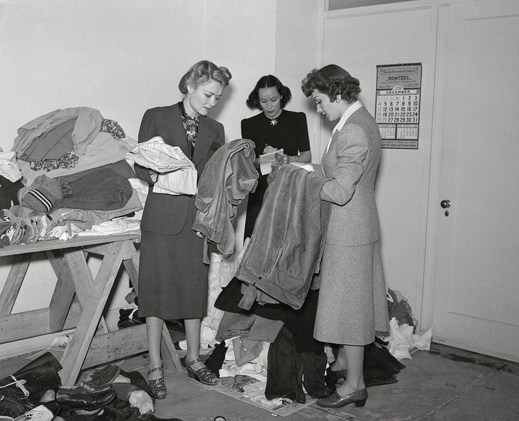 Constance Bennett with Dolores Del Rio and Claudette Colbert inspecting clothing at the Hollywood headquarters of the International Committee for refugees in France, 1940.