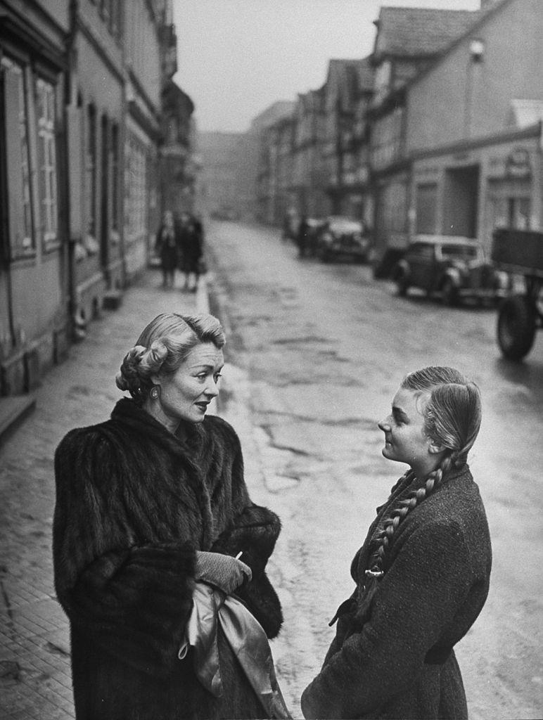 Constance Bennett speaking with a young German woman, 1949.