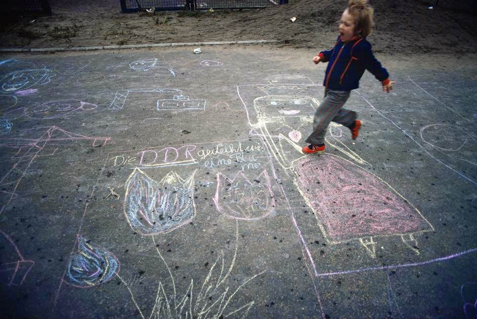 A boy playing. Paintings on asphalt in a school yard. East Berlin, 1974.