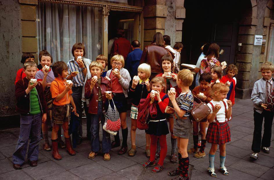 An outing of school children has ice cream in the town center. East Berlin, 1974.