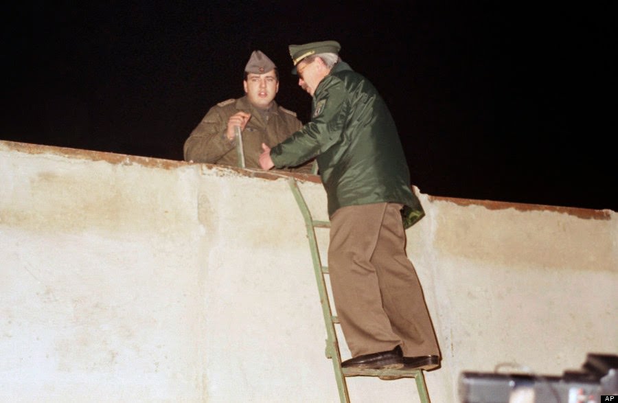 A West Berlin policeman, right, and an East German border guard stand on ladders while talking over the Berlin Wall at Bernauer Strasse in Berlin, Nov. 11, 1989
