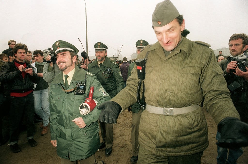 An East German border guard (R) shares a joke with a West German policeman (L) at the Potsdamer Platz (square) where a new crossing point into the West has been opened 12 November 1989