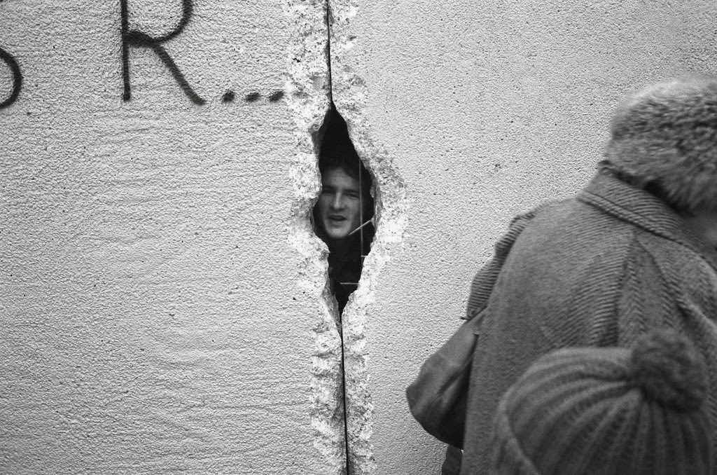 A young man peers into East Berlin though a hole in the Berlin Wall at the effective end of the city's partition, 31st December 1989.