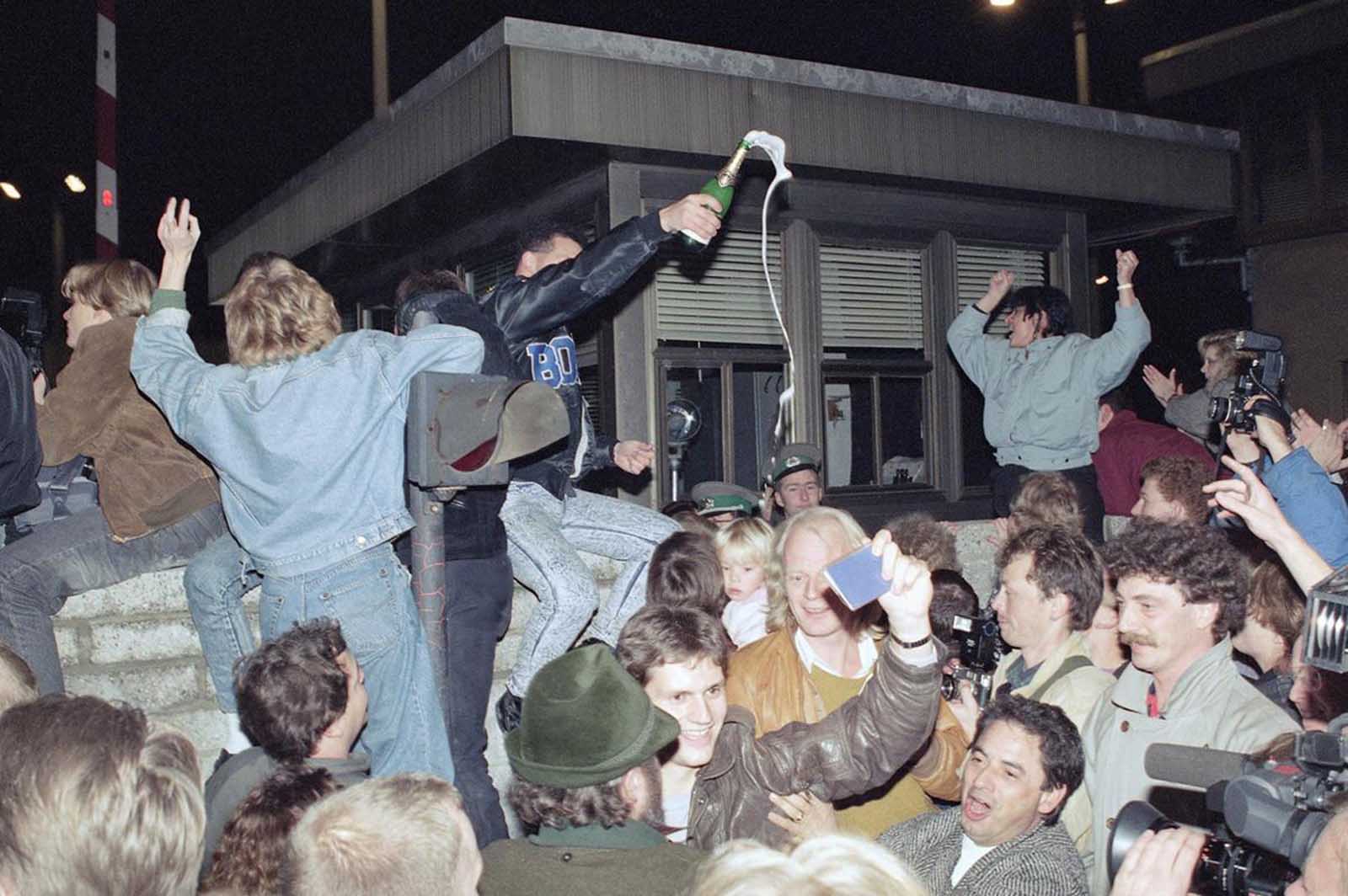 East and West Berliners mingle as they celebrate in front of a control station on East Berlin territory, on November 10, 1989.