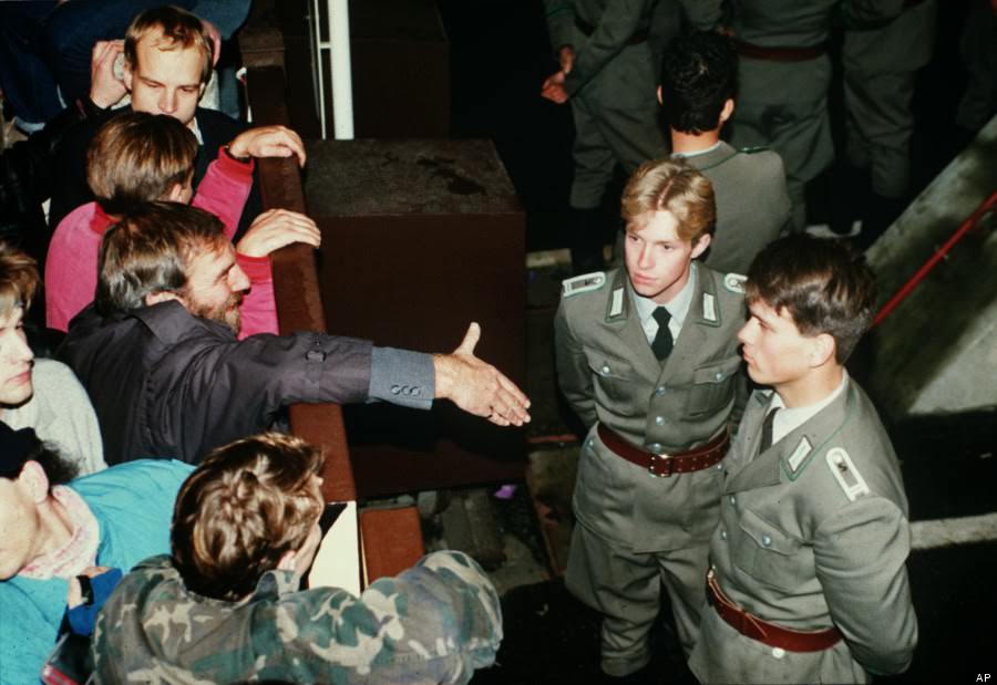 East German border policemen, right, refuse to shake hands with a Berliner who stretches out his hand over the border fence at the eastern site nearby Checkpoint Charlie border crossing point on Nov. 10, 1989.