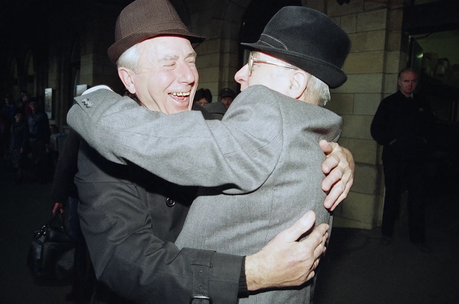 Two men from West and East Germany meet again and embrace each other after the arrival of a special train from Magdeburg at Helmstedt railway station.