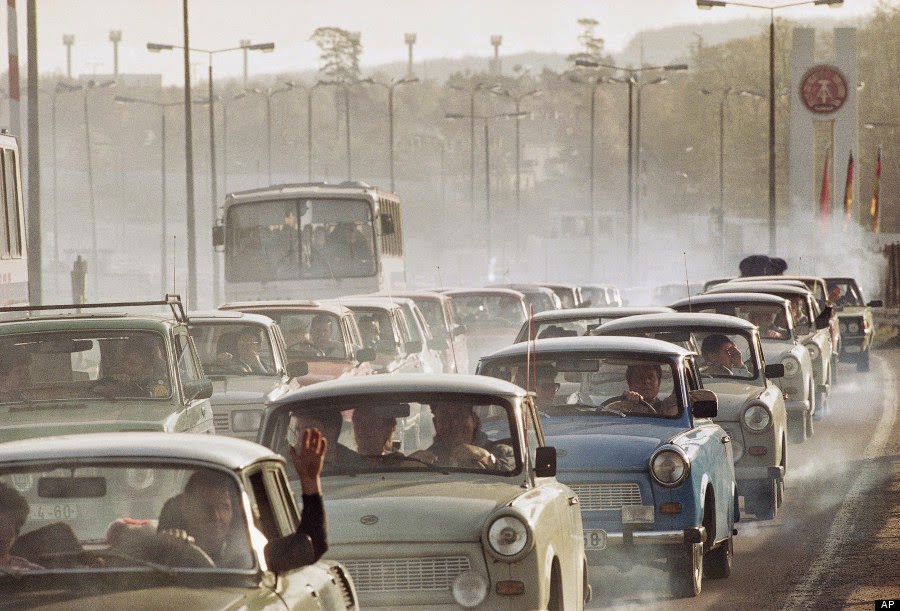 In a giant cloud of exhaust fumes of two-stroke engines, hundreds of East German cars wait bumper to bumper in front of the West German checkpoint Helmstedt to enter the west, Nov. 11, 1989.