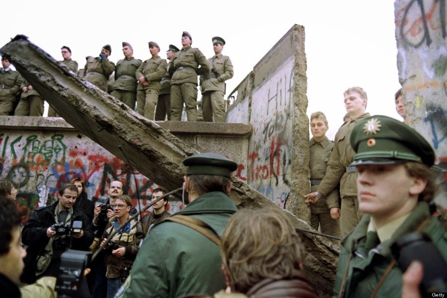 Two West German policemen prevent people from approaching as East German Vopos stand on and near a fallen portion of the Berlin Wall 11 November 1989.