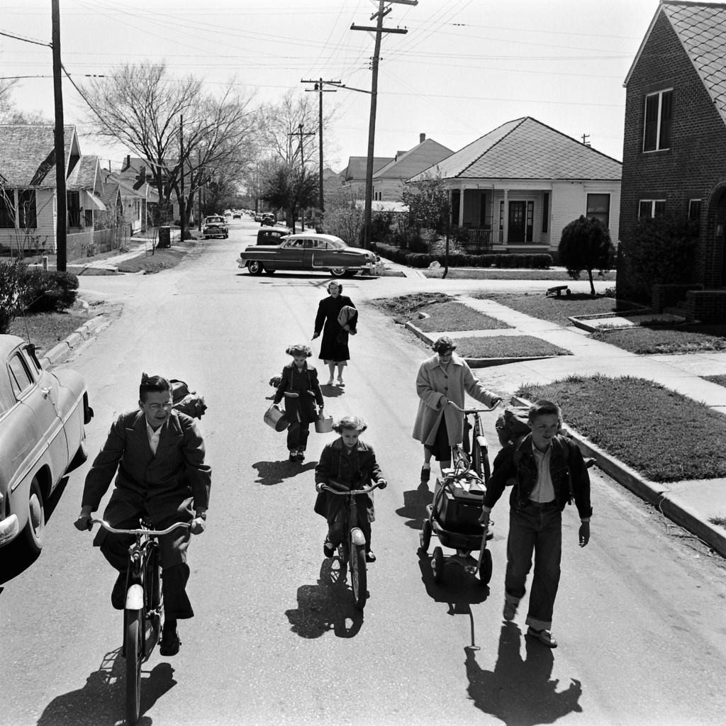 Family carrying supplies on bicycles, in backpacks, and in carts through their neighborhood in preparation for an atomic war drill at their home in Houston, March 1954.