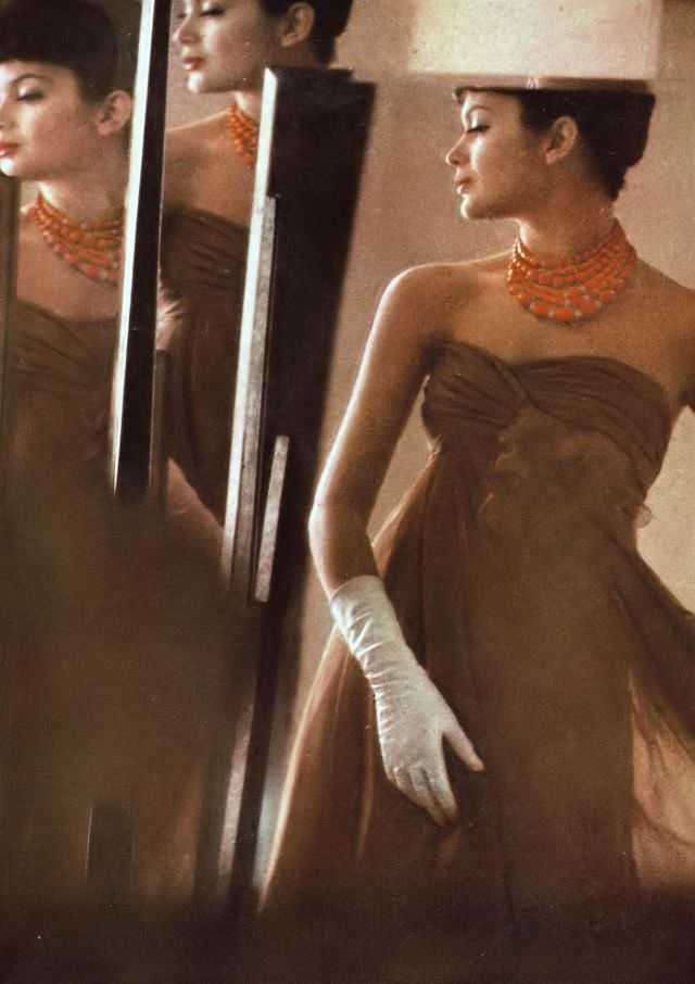 Isabella in brown silk chiffon dress, a rose marks the high corsage above the graceful flow of the skirt, by Jane Derby, necklace by Nettie Rosenstein. Harper's Bazaar, March 1959