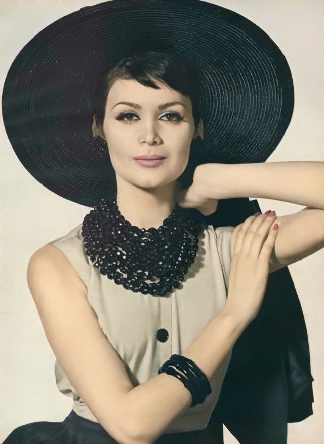 Isabella Albonico in beige and black dress and jacket of silk broadcloth by Mort Schrader, straw hat by John Frederics Charmer, jet necklaces by Marvella. Vogue, June 1959