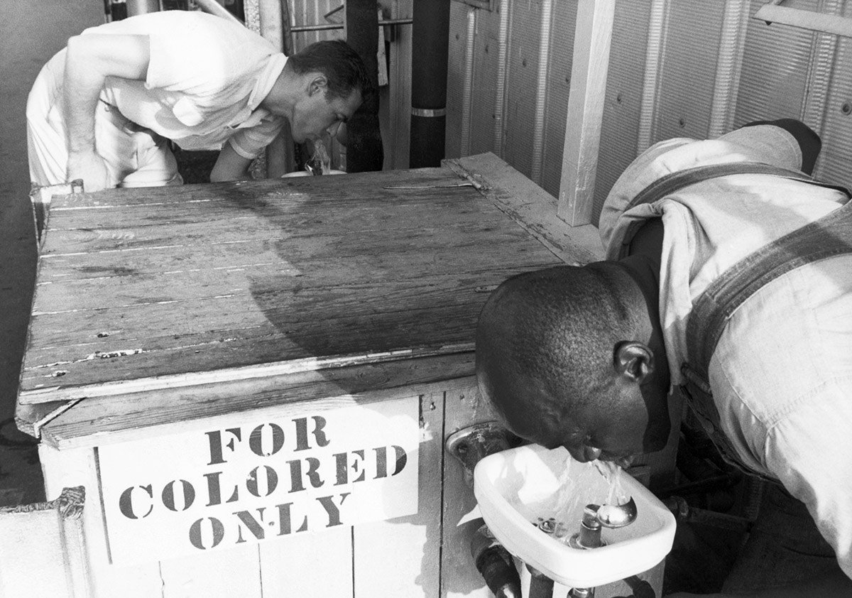 Men drink from segregated water fountains.