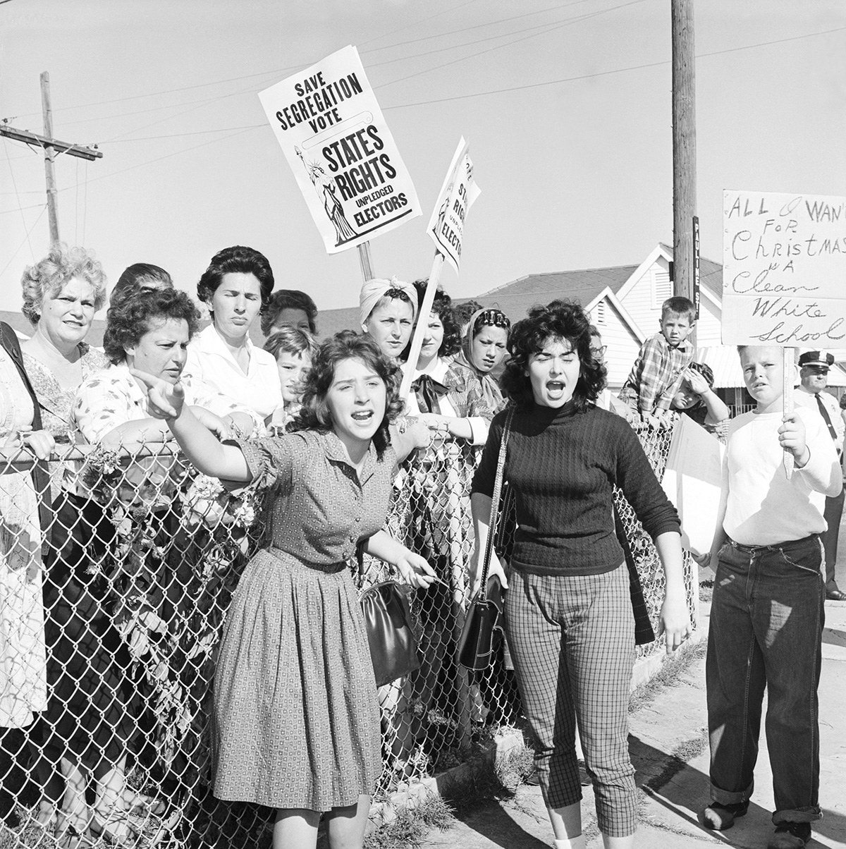 Women and teenagers at William Franz Elementary School yell at police officers during a protest against the desegregation of the school.
