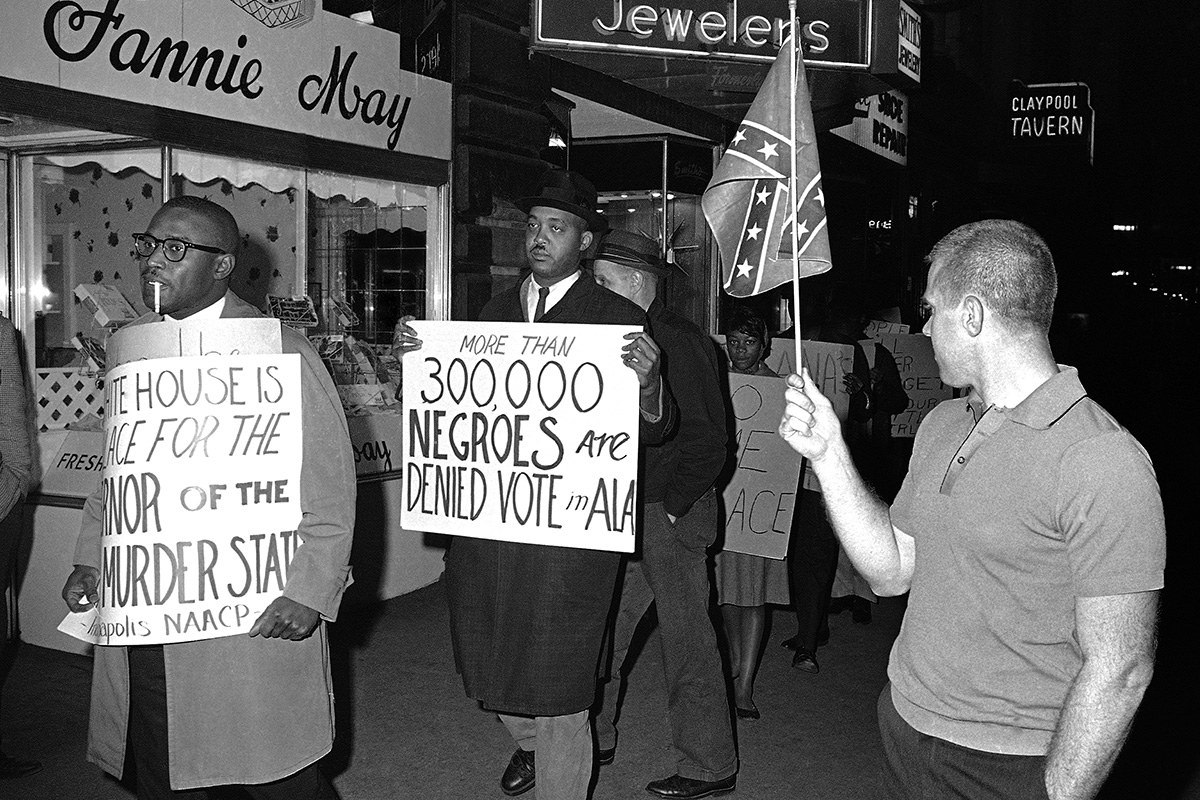 A man waves a Confederate flag before a group of demonstrators in front of an Indianapolis hotel where then-Gov. George Wallace of Alabama was staying on April 14, 1964.