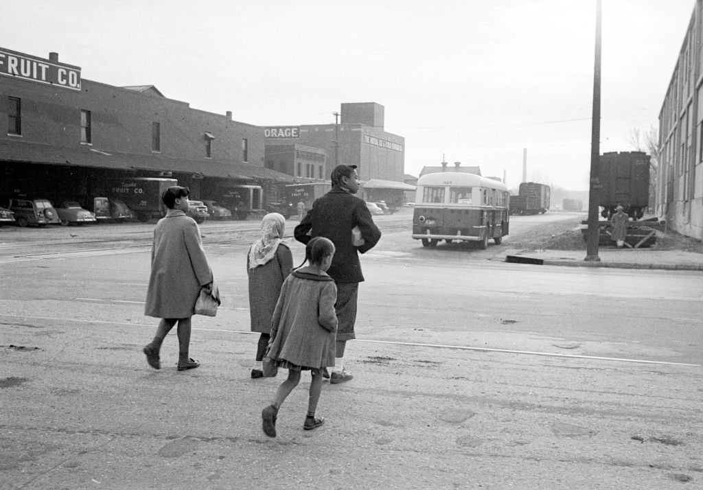 African American mother walking with children to distant school re segregation of elementary grade students throughout the state prompting famed legal suit of Brown vs. Board of Education.