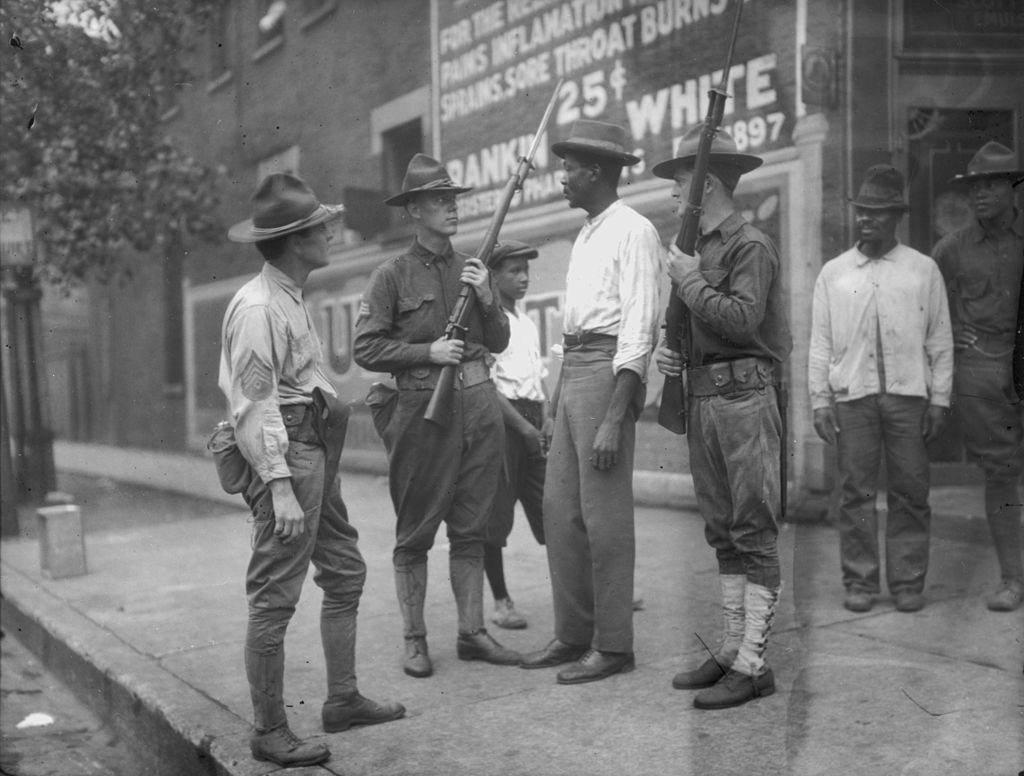 National Guardsmen, called in by Mayor 'Big Bill' Thompson after three days of rioting, question an African American man in Chicago, 1919.