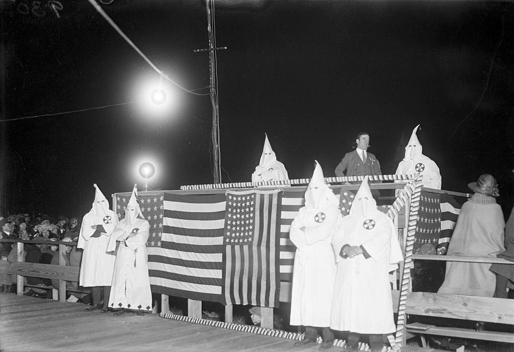 Ku Klux Klan grouped around flag draped speaker's stand at Freeport, Long Island, 1920.