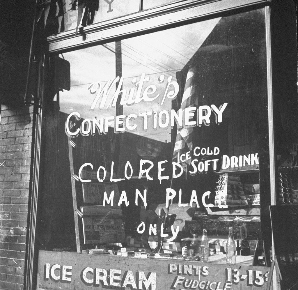 Shop window with words "colored man place only", 1943.