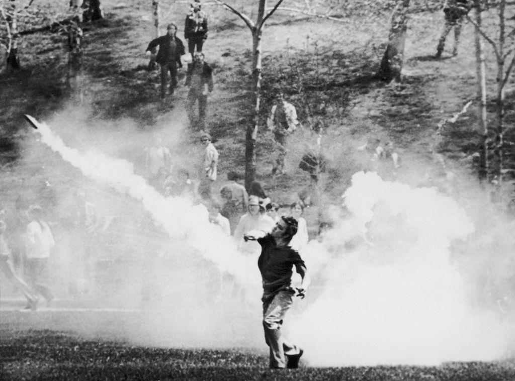 A student throws a tear gas canister back at National Guardsmen during a demonstration, 4th May 1970.