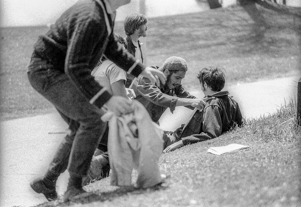 Students kneel on the grass beside wounded classmate John Cleary after the latter had been shot, May 4th 1970.