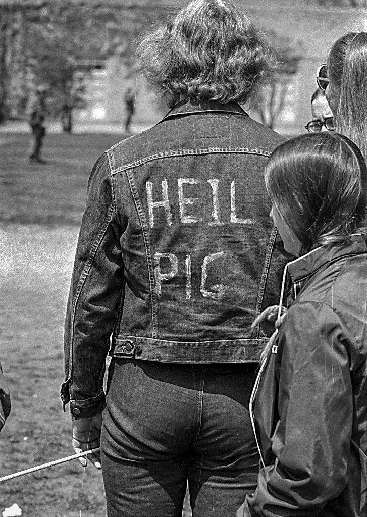An unidentified Kent State University student in a jean jacket on which is written 'Heil Pig,' a reference to the on-campus presence of the Ohio National Guard